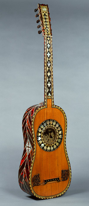 1697. Jean Baptiste Voboam.''The back, sides, neck, and peghead of this guitar are overlaid with tortoiseshell, ebony, and ivory chevrons with framed scrollwork, lozenges, and geometric banding and edging. The top has a gilded rosette bordered by a band of mother-of-pearl ornaments. Originally strung with five pairs of strings, this instrument was converted in the late eighteenth or early nineteenth century to six single courses.''