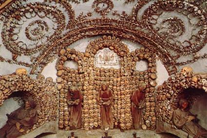 ''The bones in the six-room crypt represent over 4,000 individual monks. It is said monks fled the French Revolution (1793-94) and took refuge at the Church in Roma. There are many theories about the arrangment of the bones, but most stories end with the notion that the anonymous artist reaped his heavenly reward. One tale says that a French Capuchins did the work, no doubt mimicing the catacombs of Paris. The Marquis de Sade visited the crypt in 1775 and described it as "An example of funerary art worthy of an English mind", created "by a German priest who lived in this house."