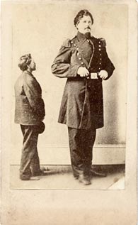 ''The carte-de-visite card below shows a giant in uniform with a "normal" man looking up at him. Without this man for scale we would not know how big he is. In the same way furniture or larger people gave scale to the photographs of midgets.  Other copies of this image are identified as Monsieur E. Bihin, a Belgian giant with great strength.''