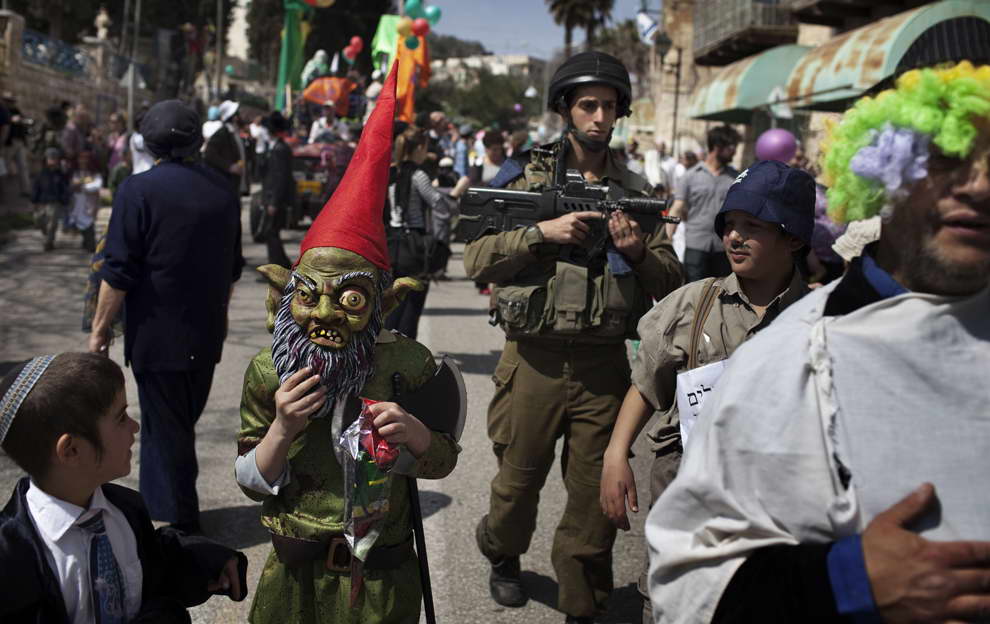 ---An Israeli soldier kept guard as Israeli settlers wearing various costumes to celebrate the annual Purim parade on March 8 in the divided West Bank city of Hebron. (Menahem Kahana/AFP/Getty Images) Read more: http://lollitop.blogspot.com/2012/04/festival-of-purim_12.html#ixzz2MIQTgV1v---